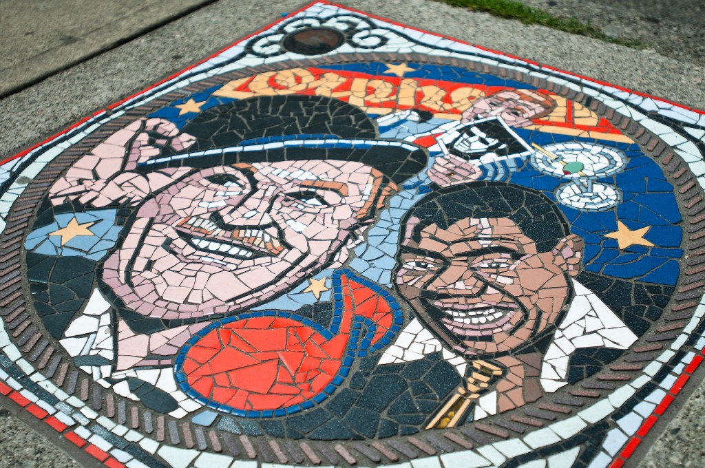 This colourful Mosaic found on Smithe Street on the south side of the Orpheum Theatre depicts some of the fun times that occurred over the years in this eighty year-old location. Popular musicians, comediennes and actors all took the stage at this Vancouver landmark and continue with the Vancouver Symphony Orchestra.  Read more: Orpheum Theatre Entertainers Mosaic https://www.venturevancouver.com/image/orpheum-theatre-entertainers-mosaic-vancouver#ixzz3hDv0dWxj